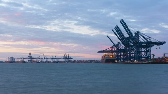 Felixstowe, United Kingdom - October 24 2021: Sunset timelapse as container cargo is loaded on-board ships at the Port of Felixstowe, amid a major worldwide supply chain crisis