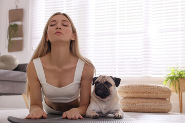 Beautiful woman with dog practicing yoga at home