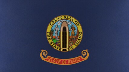 Top down view of a 9mm bullet in the center and on top of the US state flag of Idaho