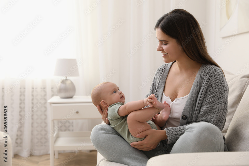 Sticker young woman with her little baby on sofa at home