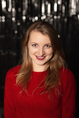 A young attractive woman in red smiles at a party, on a silver shiny background