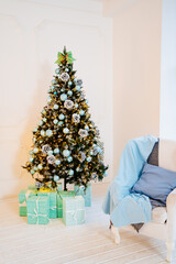 chair with blue pillow and blanket against near christmas tree with garland
