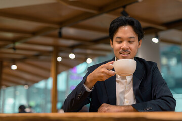 Portrait of Asian businessman in coffee shop drinking coffee