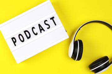 Podcast word on lightbox with headphones on yellow background, podcast concept