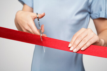 Mid section of businesswoman in blue dress cutting red ribbon - obrazy, fototapety, plakaty
