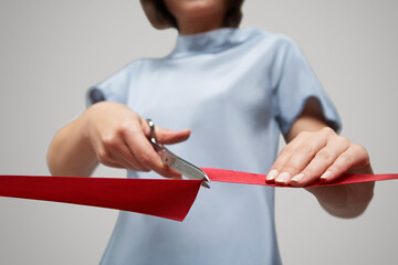 Low angle view of businesswoman in blue dress cutting red ribbon