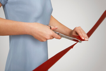 Mid section of businesswoman in blue dress cutting red ribbon