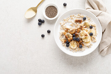 Oatmeal bowl. Oat porridge with banana, blueberry, walnut, chia seeds and almond milk for healthy breakfast or lunch. Healthy food, diet. Top view. - obrazy, fototapety, plakaty
