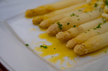 Seasonal vegetable food, cooked white asparagus served with eggs, parsley and butter