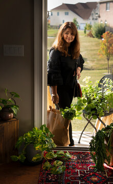 Woman entering a home with bags of groceries 