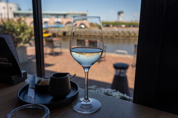 Glass of white wine served in cafe with view on harbour of Harlingen, vacation in Friesland, Netherlands