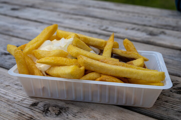 Portion of french fried potato chips with curry and mayonnaise sauce and onion