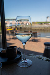 Glass of white wine served in cafe with view on harbour of Harlingen, vacation in Friesland, Netherlands