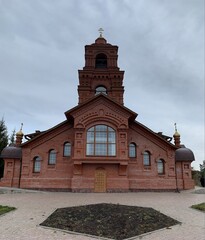 Fototapeta na wymiar Orthodox church made of red bricks with golden baths and a cross