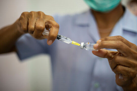Close-up of doctors, nurses, sucking vaccines from bottles, preparing to vaccinate against and cure from coronavirus, covid-19, flu, infection. Medical concept of vaccination.
