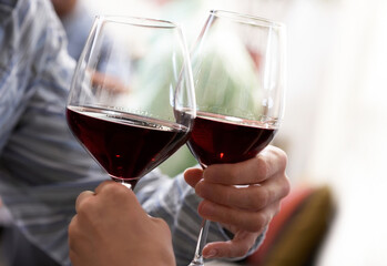 People Toasting with Red Wine, Couple Having Vine. Selective Focus of Wine Glasses
