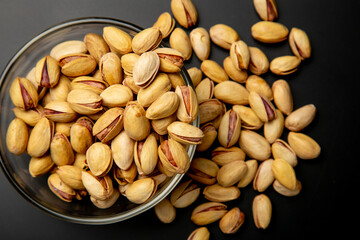 Pistachio nuts in a shell with coarse sea salt on a black background. Beer appetizer - salted nuts. concept is snacks for beer.