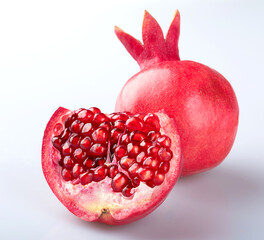 A whole beautiful fresh ripe pomegranate in a peel with a crown and a half of a pomegranate with...