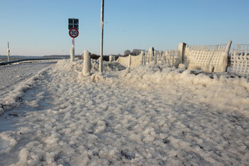 Mit Eis überzogene Straße an der Ostsee im Winter bei Bülk, Glatteis