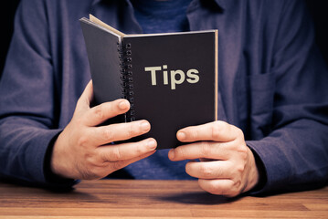 Closeup man is holding and reading the Tips Book