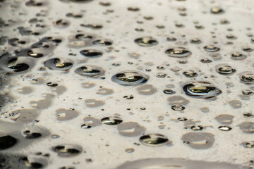 Drops of water and oil on a dark glass surface