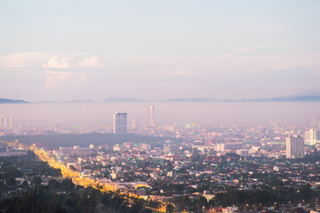 Fototapeta premium Aerial view of citscape from the top of mountain covered by the fog with horizontal line of mountain in background with sunrise in the morning