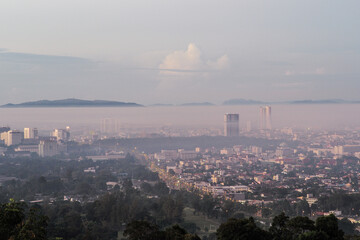 Aerial view of citscape from the top of mountain covered by the fog with horizontal line of mountain in background with sunrise in the morning