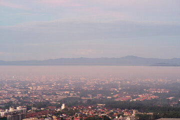 Obraz premium Aerial view of citscape from the top of mountain covered by the fog with horizontal line of mountain in background with sunrise in the morning