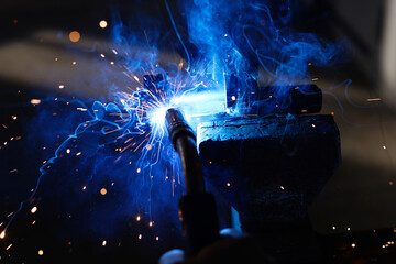 Welder's job. Sparks from welding metal on a dark background. Authentic workflow.