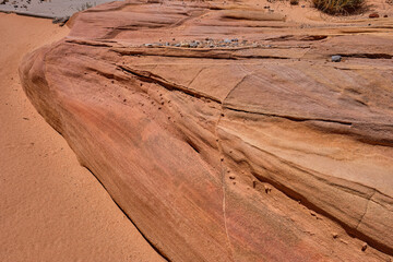 Sand, pebbles and smooth colorful rocks carved from aztec sandstone create a gully in the Nevada Desert