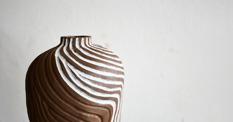 Handmade ceramic vase standing on grey table on light background. Art of clay. The process of creating pottery. Copy space