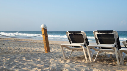 BEACH CHAIRS (CHAISE LONGUE) IN TROPICAL BEACH AREA WITHOUT PEOPLE ON THE RENA WITH NATURAL LIGHT AND SPACE FOR TEXT