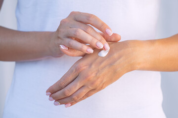 Fototapeta na wymiar Woman applying moisturizer on her dry hands. Hand cream. Skin protection. Hand care or skin care concept