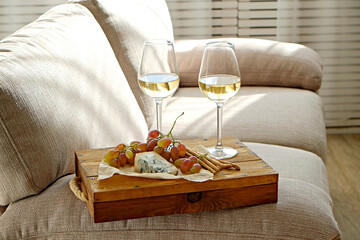 Two wineglasses of vintage chardonnay with delicious appetizers. Couple of glasses of white wine, italian breadsticks, figs and grapes. Interior background. Close up, copy space.