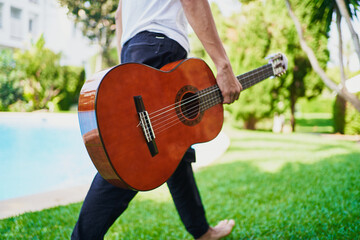 Guitarist with guitar walking on grass in yard