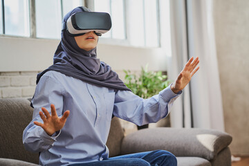 Muslim woman sitting on a couch and using a VR headset
