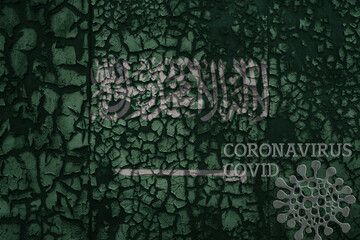 flag of saudi arabia on a old metal rusty cracked wall with text coronavirus, covid, and virus picture.