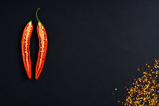 Single Red Hot Chilli Pepper cut lengthways with seeds placed on low key black minimalistic background