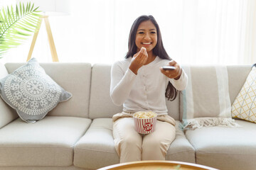 woman eating popcorn watching favorite television show sitting cozy couch