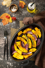 Pumpkins slice with rosemary and purple onion, baking fresh healthy food with spice on a dark stone background. Keto or paleo diet veggie vegan or vegetarian. Top view flat lay background.