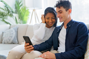 Loving young couple sitting on the couch at home and using telephone