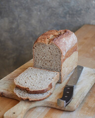 homemade whole wheat bread, tin loaf, sliced on a wooden board on the kitchen table