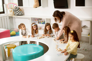 Group of cute little kids playing with preschool educational toys with kindergarden teacher