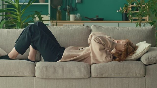 Depressed and Desperate Teenage Girl Wrapping Her Head in Her Arms on the Living Room Couch at Home. Physical and Emotional Abuse, Aggression, Cyberbullying From Social Networks. Mental Health.