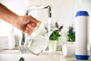 Hand filling jug from a tap with filtered osmosis water - obrazy, fototapety, plakaty