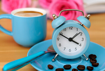 blue espresso cup and alarm clock with spoon and coffee beans and roses like romantic concepr coffee time or time for coffee