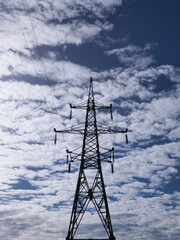 Electrical high-voltage tower on cloudy sky background.