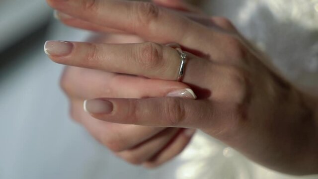 Bride puts the ring on her finger. Wedding ring in white gold or silver with a diamond on the hand. Girl in a wedding dress.