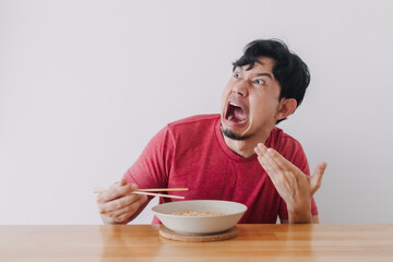 Fototapeta na wymiar Funny face of Asian man eat very hot and spicy instant noodle.