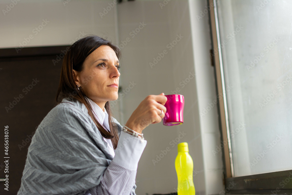 Wall mural Woman drink coffee near window.